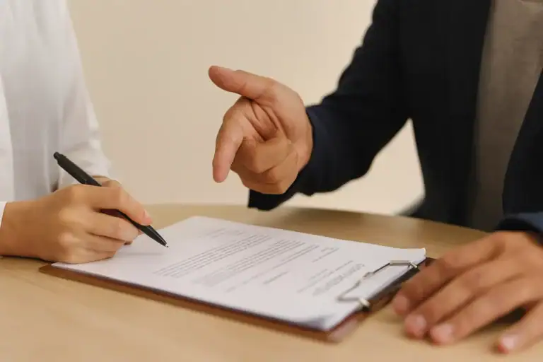 Finanziamento sbagliato consulente indica un documento mentre un cliente firma un contratto di finanziamento su un tavolo.