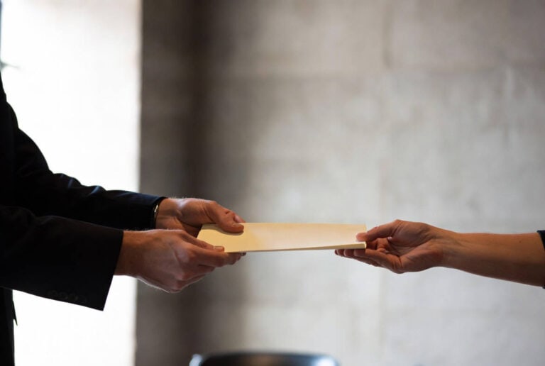 Mediatore creditizio OAM consegna un documento a un cliente in un ambiente istituzionale