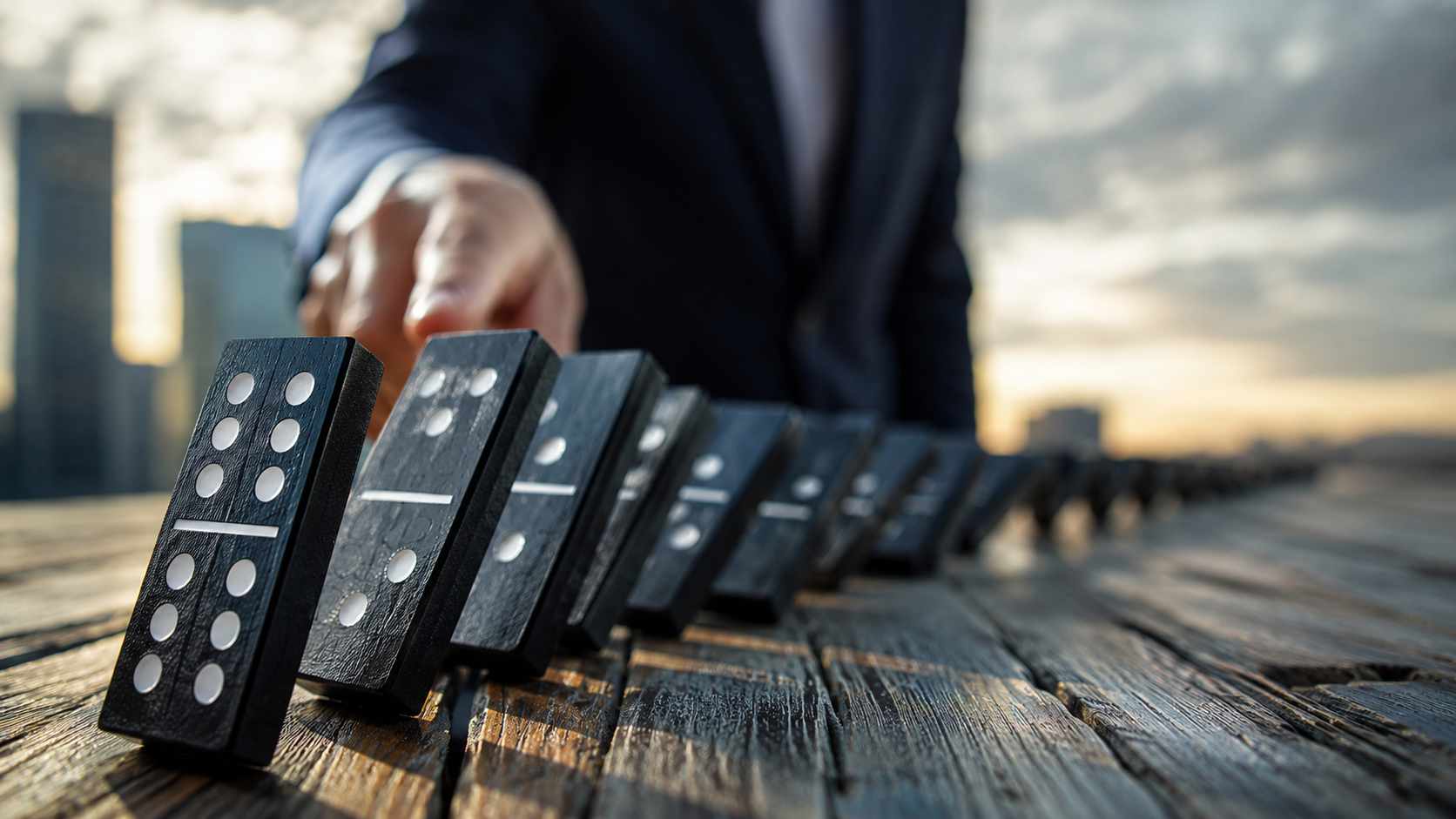 CSRD per le PMI: tessere del domino in caduta su un tavolo con una figura sfocata sullo sfondo